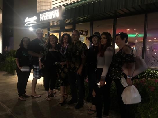 Friends are enjoying a fun night out, standing together outside a bustling restaurant.