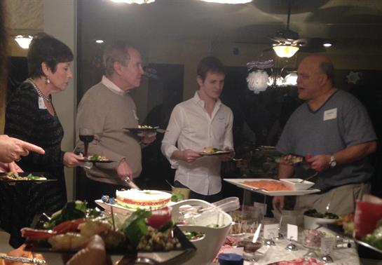 Friends gather for a cozy dinner at home, enjoying each other's company in the evening.