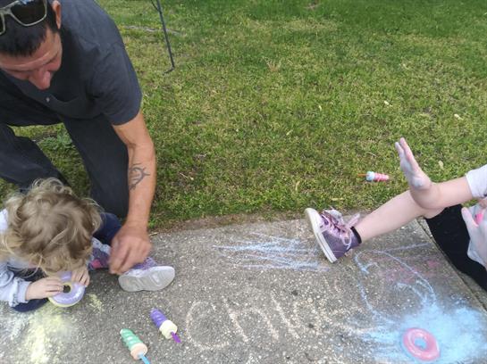 Kids are enjoying a fun afternoon outdoors using sidewalk chalk to create vibrant artwork.