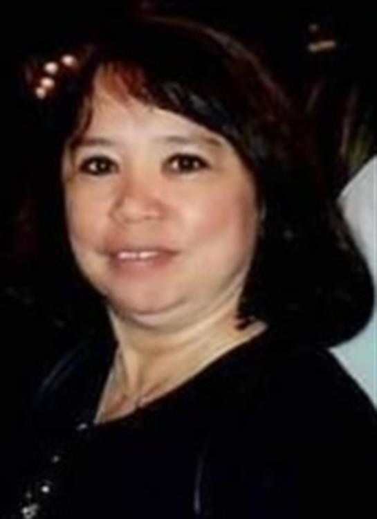 A woman with dark hair smiles warmly while participating in a friendly social event.