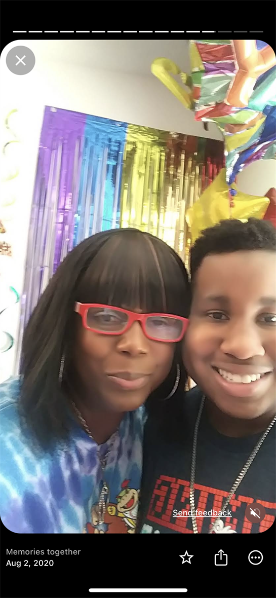 Two friends smile amid colorful streamers and balloons at a celebration.