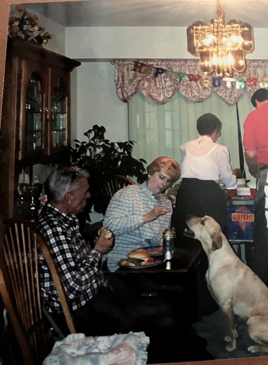 A group of people sitting at a table with a dog