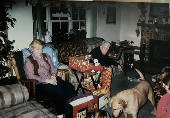 A couple of people sitting in a living room with dogs