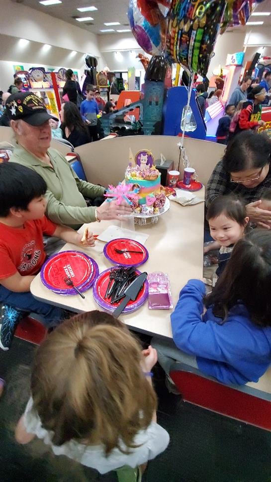 A joyful birthday party with children and adults enjoying cake, treats, and each other's company.
