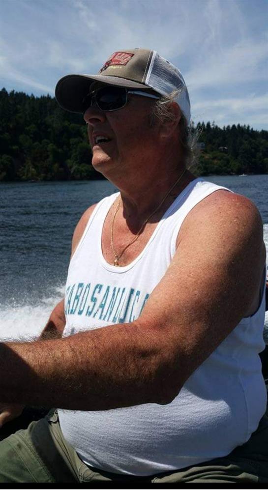 A man in a tank top is guiding a boat along the river, enjoying the sunny weather and tranquility.