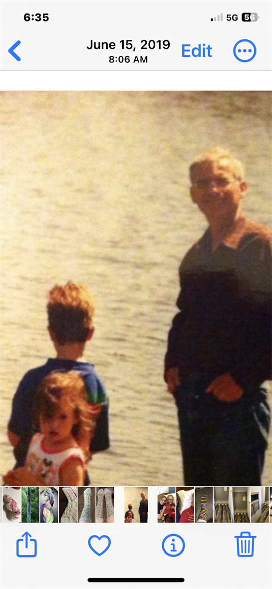 Two children and an adult stand by the lake, enjoying a sunny day and nature's beauty.