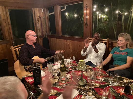 Friends gather around a table enjoying music and lively conversation while celebrating together.