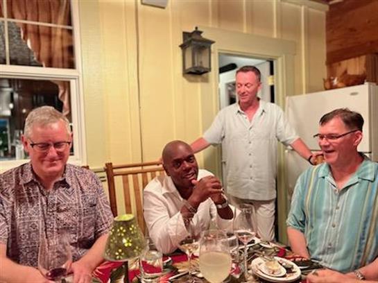 Friends are gathered around a table, sharing laughter and food in a relaxed atmosphere.