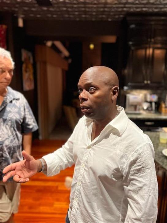 One man passionately speaks while another listens intently in a modern kitchen.