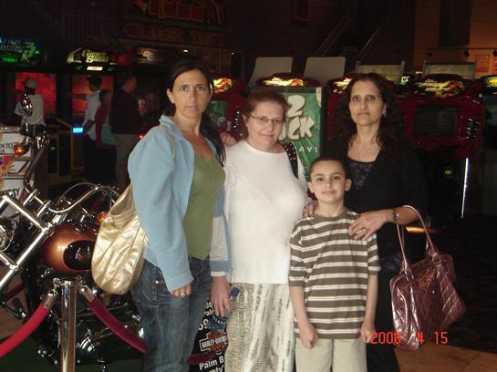 Group of four people smiling and posing in front of motorcycles during a fun visit to an arcade.