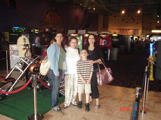 Four family members pose together in an arcade filled with various games and attractions.