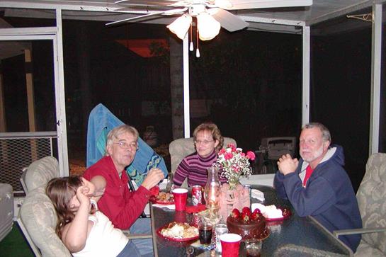 Friends and family sit around a table sharing food and laughter in a warm, inviting atmosphere.