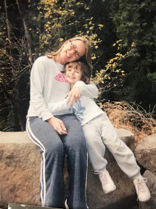 Two family members joyfully embrace on a rock in the forest, showing love and happiness.