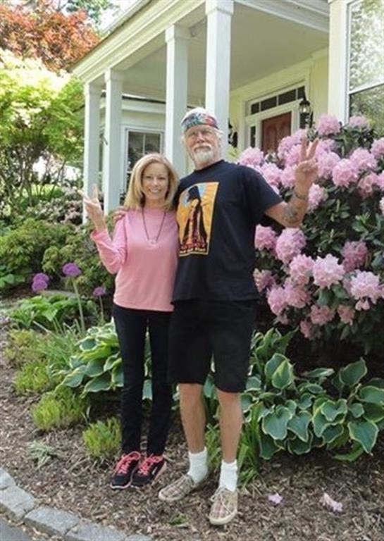 Friends pose happily in a beautiful garden surrounded by colorful blossoms on a sunny day.