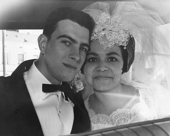 Couple enjoys their wedding day with joyful expressions inside classic car under warm sunlight.
