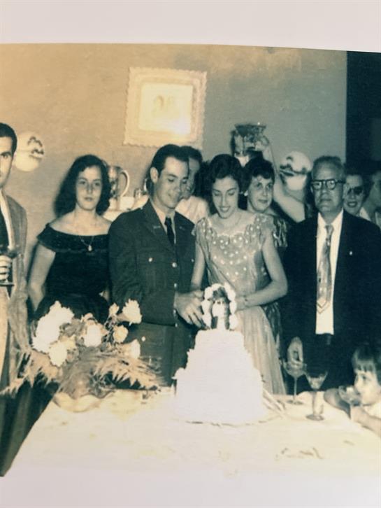 Group of people gathered to celebrate with a cake at a festive gathering in the 1960s.