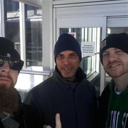 Three friends posing outside a modern building on a sunny winter day, sharing smiles and laughter.