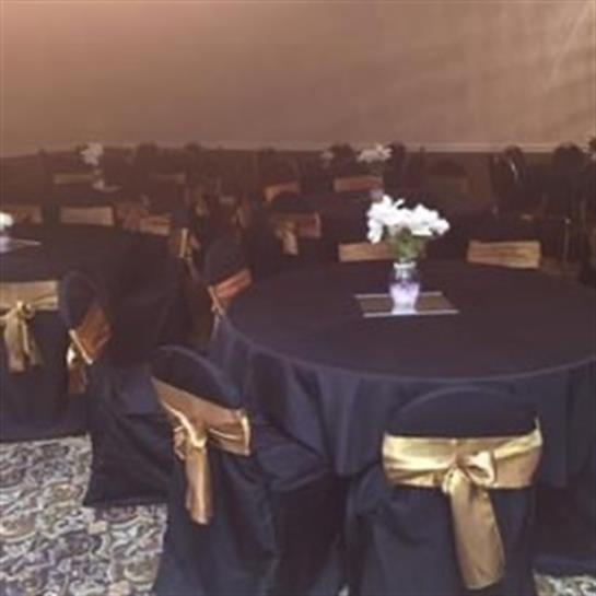 Tables are elegantly arranged with black linens and gold accents, ready for guests at a gathering.