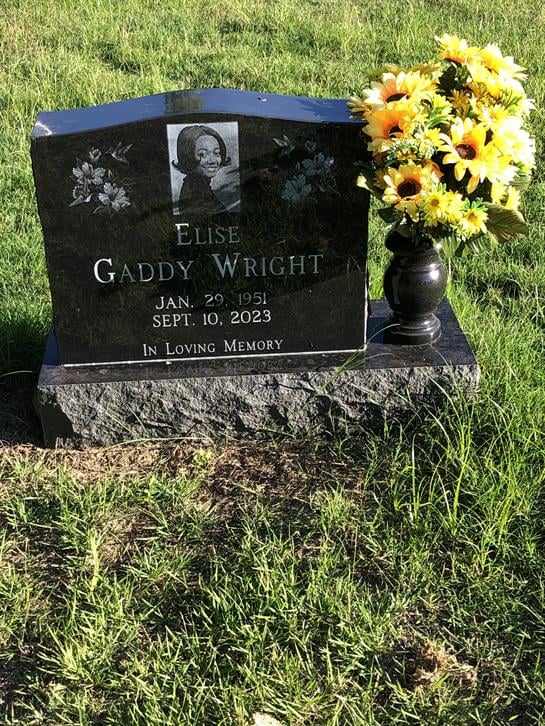 A black memorial stone honoring Elise Gaddy Wright features flowers and a heartfelt message.
