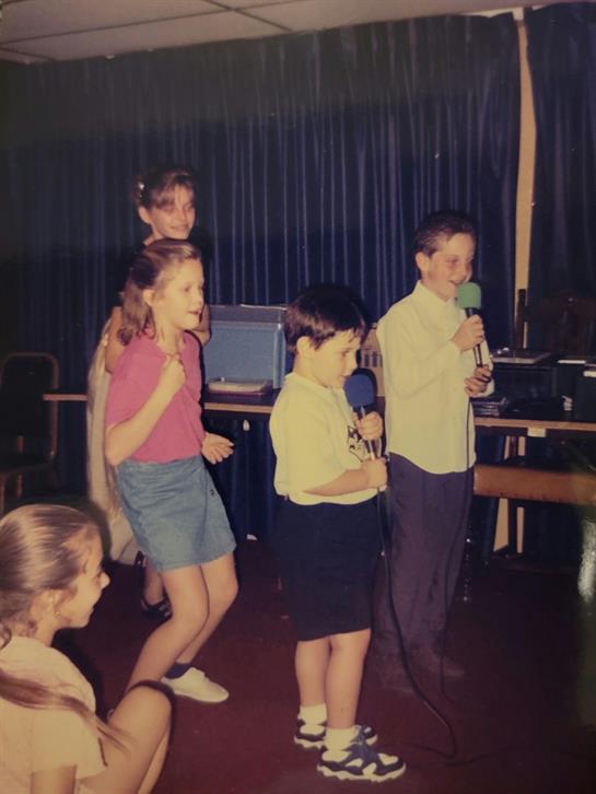 Children enthusiastically participate in a karaoke session, singing and dancing together.