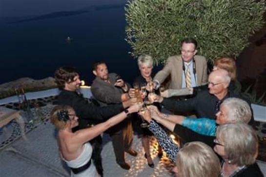 Friends raise their glasses in celebration at a beautiful outdoor venue near the water.