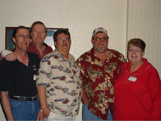 Five friends gather at a reunion, smiling brightly in their festive outfits.