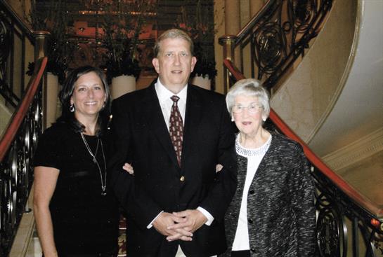 Three family members pose together in a beautifully decorated venue with ornate details.
