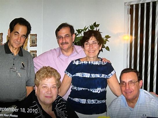 Six family members enjoy a joyful moment in a living room, sharing smiles and laughter.