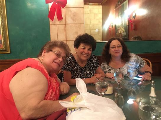 Three friends smiling and sharing a meal at a restaurant during a festive celebration.