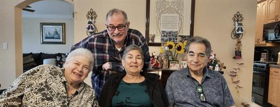 Four friends gather in a bright living room, sharing laughter and stories surrounded by mementos.