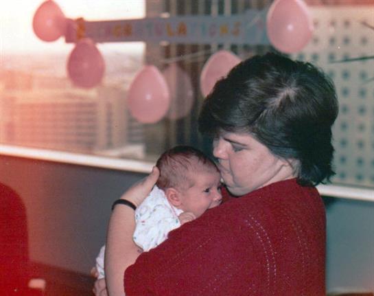Mother lovingly holds her newborn against a backdrop of balloons, enjoying a special moment.