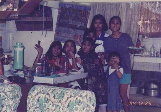 Women and children are happily celebrating together at a table filled with food and drinks.