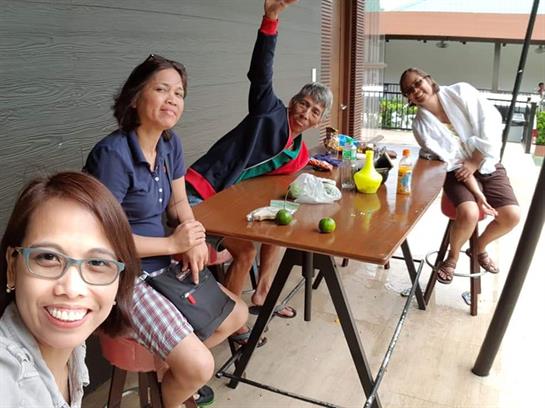 Four friends sit at a cafe table, sharing laughter and drinks in a lively outdoor setting.