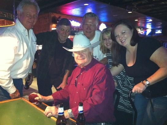 Friends gather around a pool table, celebrating and having fun in a vibrant bar setting.