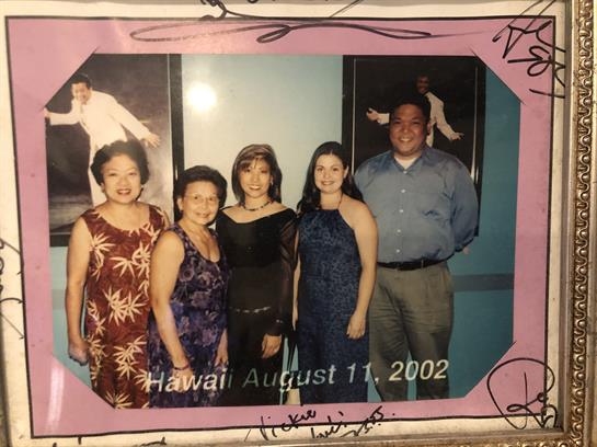 Friends are gathered, smiling and dressed in formal attire at a gathering in Hawaii.