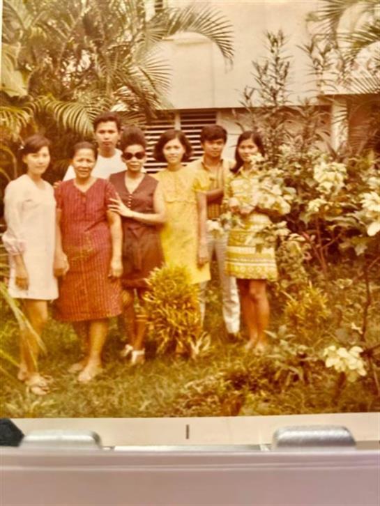 Friends gather in a lush garden, smiling and enjoying each other's company on a sunny day.