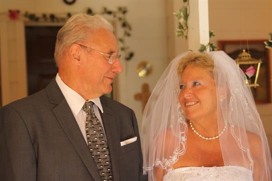 A couple stands together at their wedding ceremony, exchanging joyful smiles in an elegant setting.
