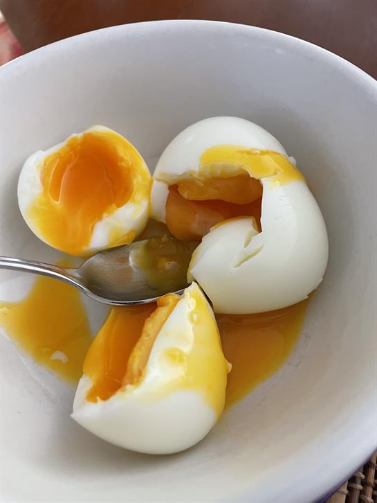 Soft boiled eggs sit in a bowl, their yolks oozing out, ready to be enjoyed for breakfast.