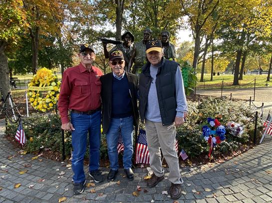 Friends gather for a memorable photo at a memorial park during a sunny autumn day.