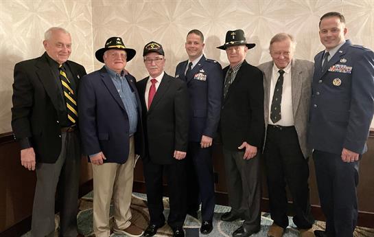 A group of six veterans stands together in formal attire, showcasing camaraderie at an event.