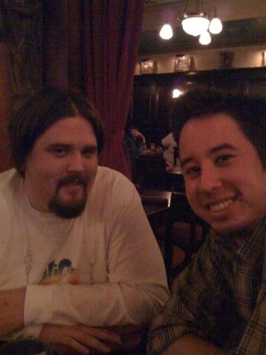 Two friends sit close, smiling and enjoying each other's company in a cozy restaurant.