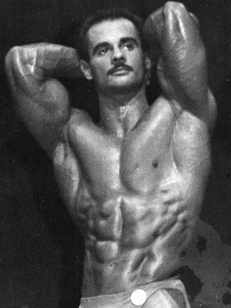 A bodybuilder proudly poses with a defined body showcasing muscles and strength at a competition.