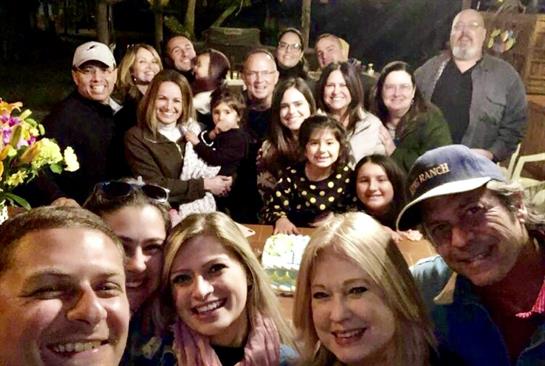 A large group of friends enjoys a joyful gathering indoors, smiling and celebrating together.