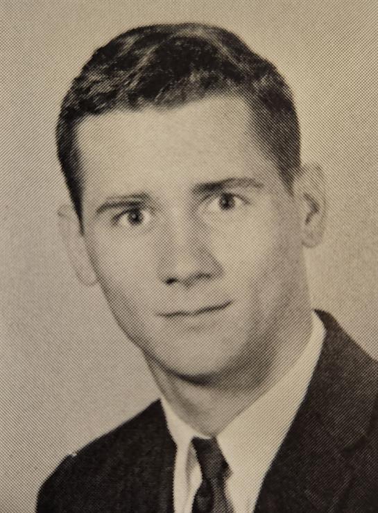 This young man poses in a suit with an engaging expression, highlighting vintage fashion.
