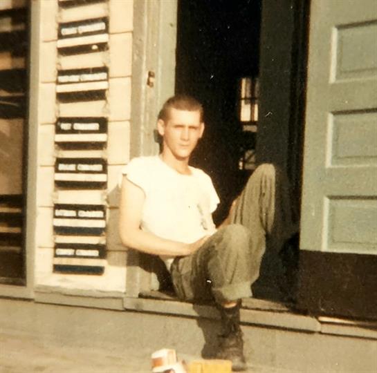 A young man sits casually on the steps of a building, enjoying a sunny afternoon.