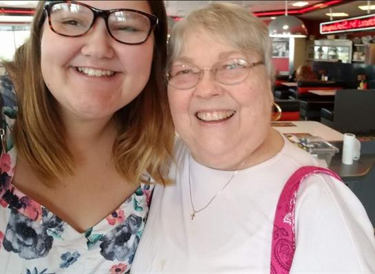 Two family members are enjoying each other's company at a bustling restaurant, smiling together.