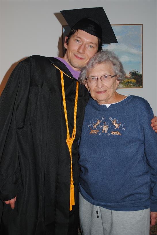 A man in a graduation gown and cap with an elderly woman