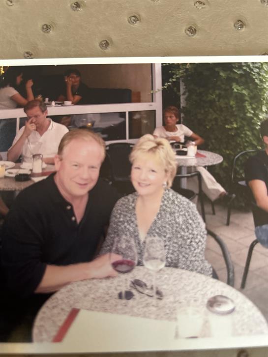A couple shares a moment at an outdoor cafe, sipping wine and smiling together joyfully.