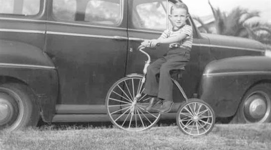 A young boy riding a tricycle