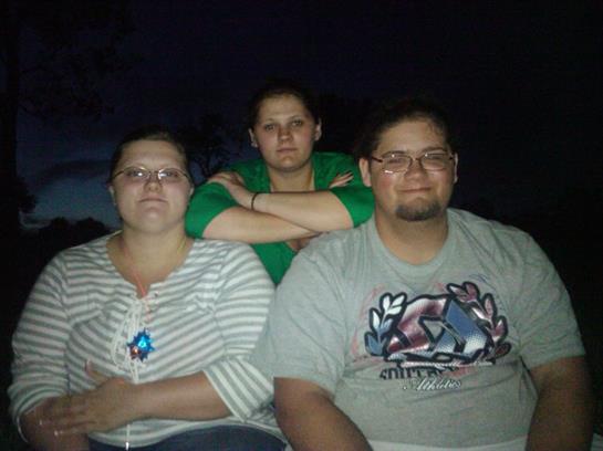 Three people pose for a photo on a boat in the dark, showcasing a casual and relaxed mood.